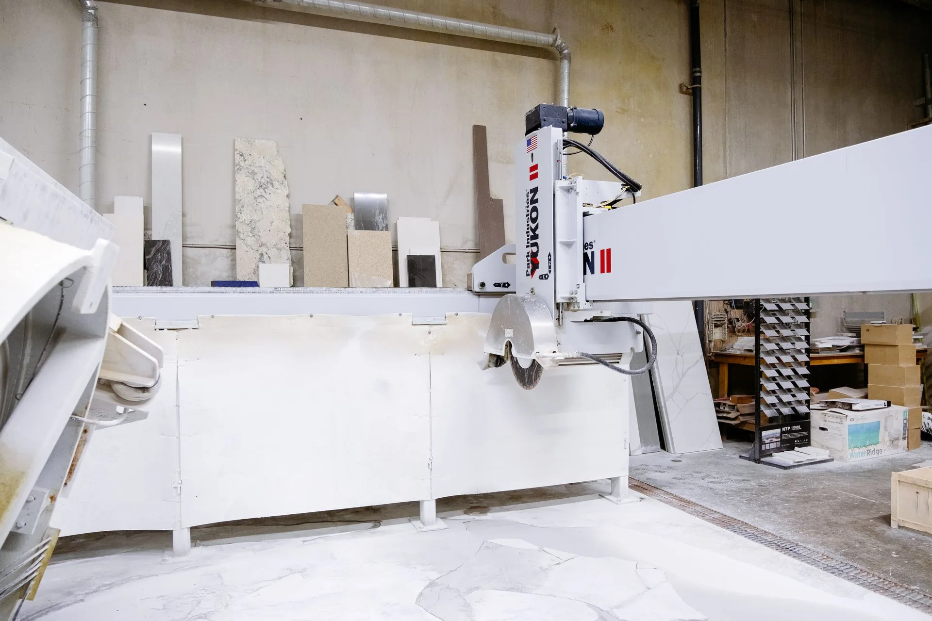 A bridge saw and stone slabs in a countertop fabrication workshop
